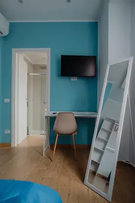 a bedroom with a blue wall with a desk and a chair at Sarina's apartment in Palermo