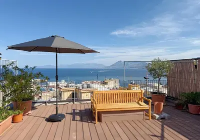 a wooden bench sitting on a deck with an umbrella at Solemar Sicilia - Casa Sabine in Santa Flavia