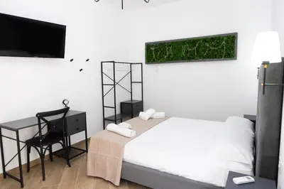 a bedroom with a bed and a desk and a television at Adagos in Palermo