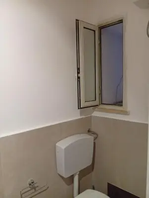 a bathroom with a toilet and a window at Casetta Professa Centro in Palermo
