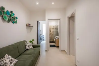 a living room with a green couch and a hallway at A' meusa Palermo Historic Center Check-in 24h in Palermo