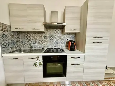 a kitchen with white cabinets and a sink and a stove at Dimora Sant'Agostino in Palermo