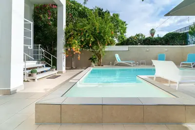 a swimming pool in a patio with two chairs and a table at Luxury apartment Villa Vera Mondello - Palermo in Mondello