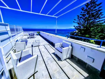 a balcony with chairs and a table and the ocean at Sunset in Santa Flavia
