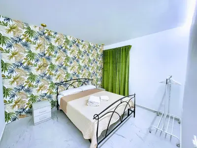 a bedroom with a bed with a tropical wallpaper at Pearl in Santa Flavia