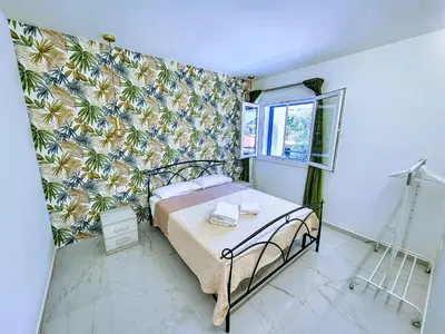 a bedroom with a bed with a tropical wallpaper at Pearl in Santa Flavia