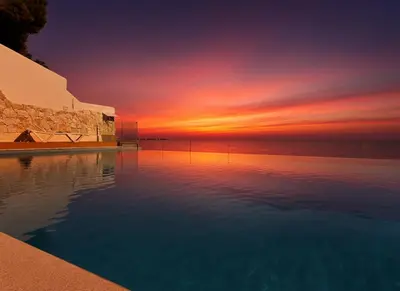 a swimming pool with a sunset in the background at Pearl in Santa Flavia