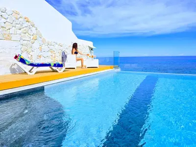 a woman sitting in a chair next to a swimming pool at Pearl in Santa Flavia