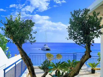 a boat in the ocean with a balcony with trees at White Coral in Santa Flavia
