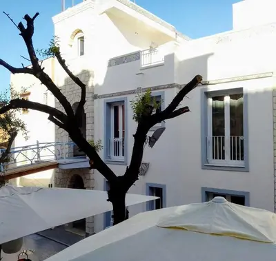 a white building with a tree in front of a table at Al Baglio di Sant'Elia in Santa Flavia