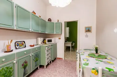 a small room with a table and a kitchen at Holiday Apartment My House in Palermo