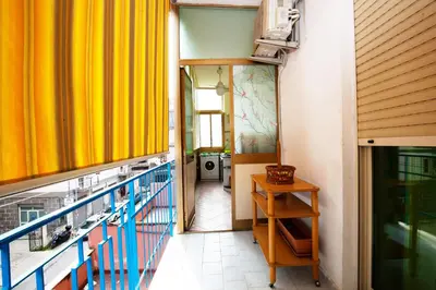 a balcony with a yellow curtain and a laundry room at Holiday Apartment My House in Palermo