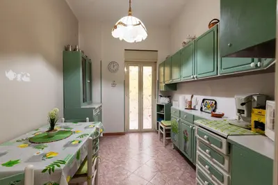 a kitchen with green cabinets and a table in it at Holiday Apartment My House in Palermo