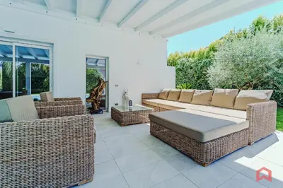 a patio with wicker furniture on a white house at Esclusiva Villa con Piscina Privata a Mondello in Palermo