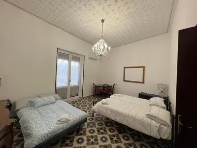 a bedroom with two beds and a chandelier at Cluverio House Apartment in Palermo