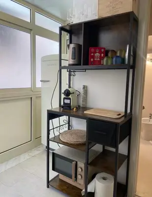 a shelf in a kitchen with a microwave and a refrigerator at Casa Levante in Palermo