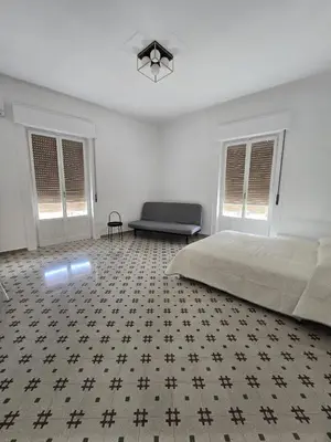 a bedroom with a bed and a couch and windows at GiuAdel casa Palermo in Palermo