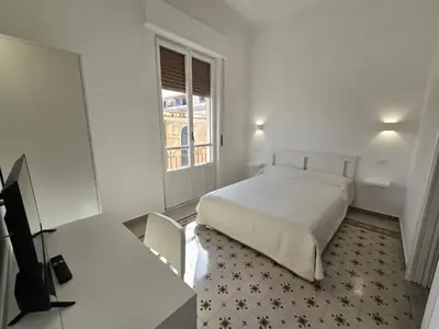 a white bedroom with a bed and a window at GiuAdel casa Palermo in Palermo