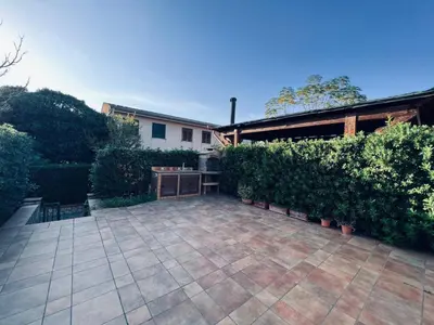 a patio with a table and some bushes at Casa Vacanza Pinto a 80 mt dal mare in Campofelice di Roccella