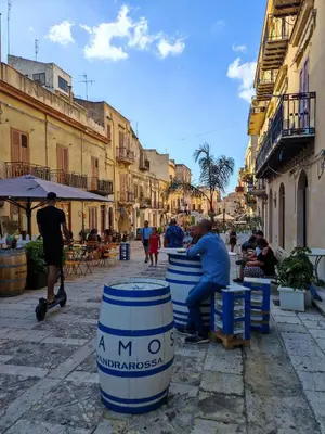 a group of people sitting around barrels on a street at A casa di Adele in Castellammare del Golfo