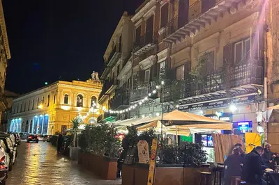 a city street at night with people sitting at tables at La Casa di Orlando Palermo in Palermo