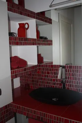 a red tiled bathroom with a sink and a mirror at Imbriani103 in Cinisi