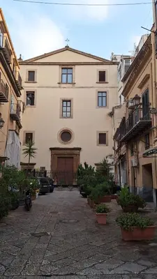 a large white building with a door in a courtyard at San Marco Rooms in Palermo