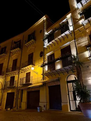 a yellow building with windows and balconies at night at Seraphia Apartment in Palermo
