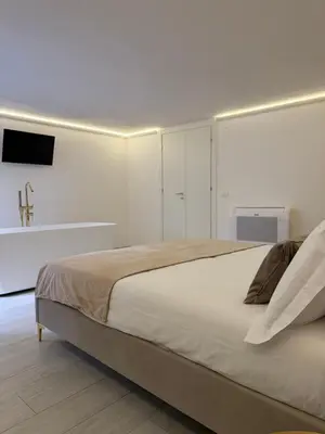 a white bedroom with a bed and a tv at Seraphia Apartment in Palermo