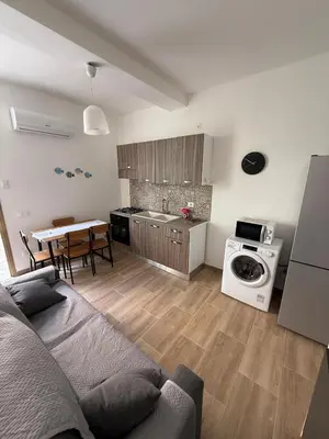 a living room with a couch and a kitchen with a washing machine at La Finestra Sul Tirreno in Terrasini