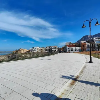 a street light on a sidewalk next to the ocean at La Finestra Sul Tirreno in Terrasini