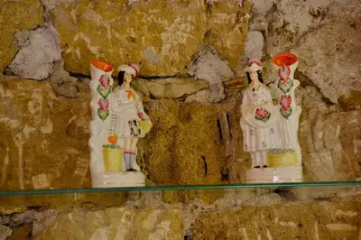 two figurines on a glass shelf on a stone wall at Massimo Secret Garden in Palermo
