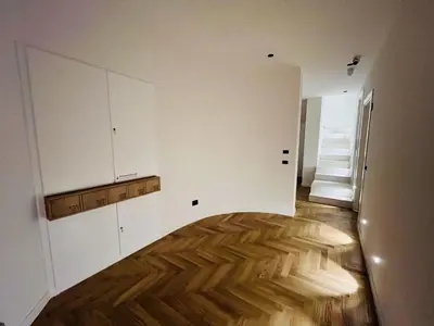 a kitchen with white cabinets and a wooden floor at Design Villa with private pool in Carini