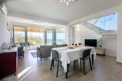 a dining room and living room with a table and chairs at VILLA DEI SOSPIRI 4, Emma Villas in Castellammare del Golfo