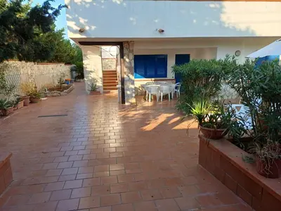 a patio with a table and chairs in a house at Villa sul mare in Isola delle Femmine