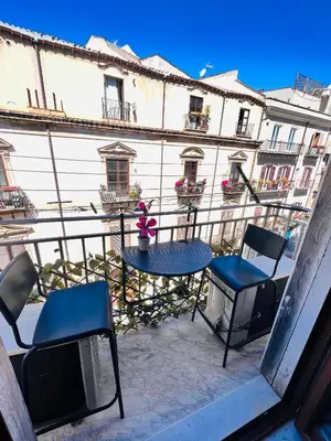 a patio with a table and chairs on a balcony at Kasa Kaletta Rooms in Palermo