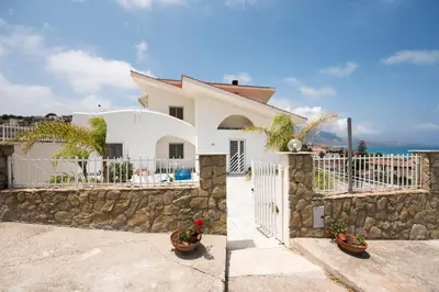 a white house with a stone wall and a fence at Villa Cielo d'Alcamo Marina in Alcamo