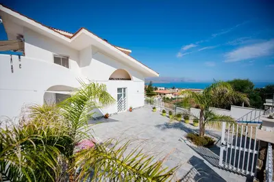 a white house with a balcony with the ocean in the background at Villa Cielo d'Alcamo Marina in Alcamo