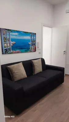 a black couch in a living room with a painting on the wall at Siciliano Palace - Deluxe Apartments & Spa in Bagheria