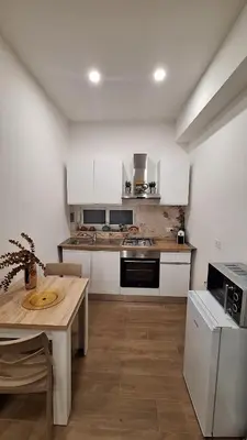 a kitchen with white cabinets and a wooden table at Siciliano Palace - Deluxe Apartments & Spa in Bagheria