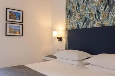 a bedroom with a bed with a headboard and two pictures at URBAN Palermo DOWNTOWN in Palermo