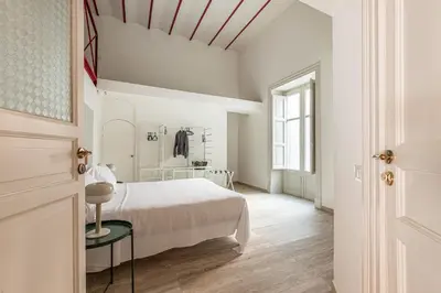 a white bedroom with a bed and a table at Central City Apartment by Wonderful Italy in Palermo