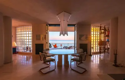 a dining room with a table and chairs and the ocean at Modernist Villa With Private Sea Access in Bagheria