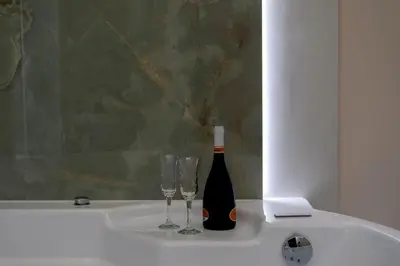 a bottle of wine and two glasses on a bath tub at Isidoro Luxury Suites in Palermo