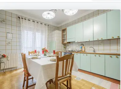 a kitchen with a table and chairs and a kitchen with blue cabinets at incantevole casa vacanze myu in Cinisi