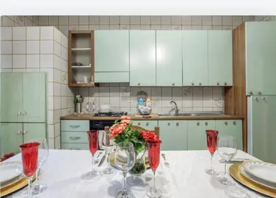 a kitchen with a table with wine glasses and flowers at incantevole casa vacanze myu in Cinisi