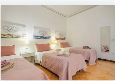 two beds in a room with pink sheets at incantevole casa vacanze myu in Cinisi