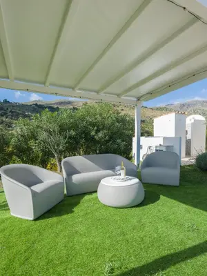 a patio with two chairs and a table on grass at Villa Aura Scopello in Castellammare del Golfo