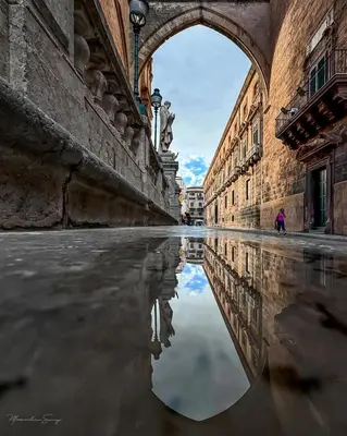 an alley with a reflection of a person in the water at SottoCapo House in Palermo