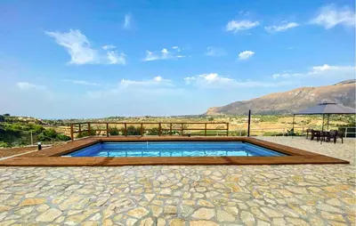 a swimming pool with a table and an umbrella at Villa Bruno in Castellammare del Golfo